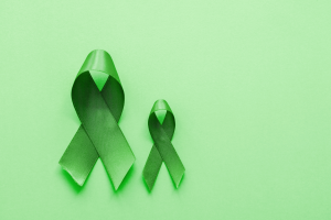 two green charity support ribbons against a green background, one larger than the other, supporting mental health awareness